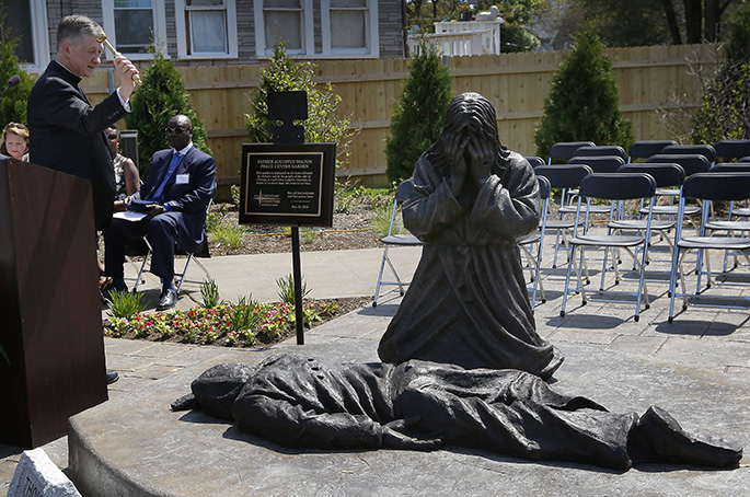 Cardinal Cupich blesses a statue of Jesus weeping over a gunshot victim at Catholic Charities' new Father Augustus Tolton Peace Center on May 24, 2018.