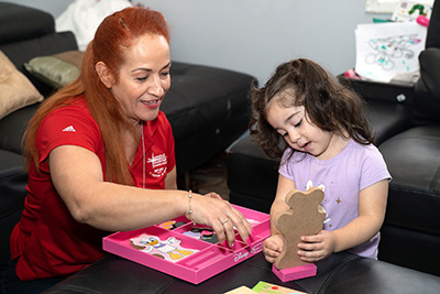 Guadalupe Fuentes of Catholic Charities plays with Yasmin during a development session at the Arts of Living Institute. Photo provided.